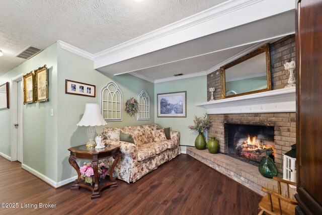 living room featuring visible vents, ornamental molding, wood finished floors, a textured ceiling, and a brick fireplace