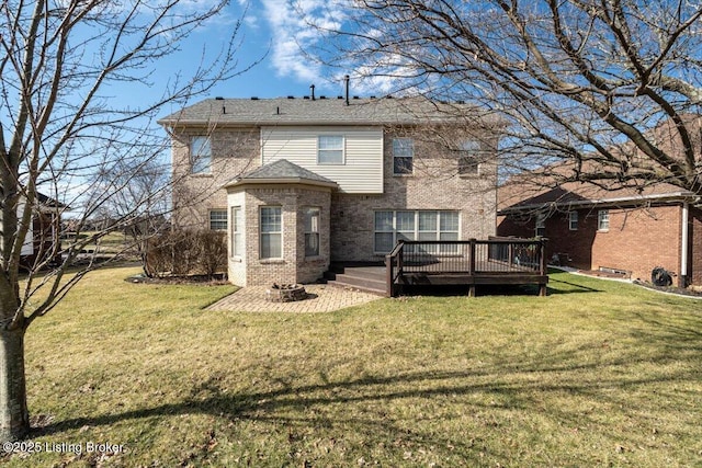 rear view of house featuring a yard, an outdoor fire pit, a wooden deck, and brick siding