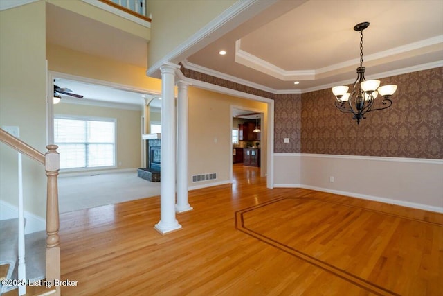 unfurnished dining area featuring wallpapered walls, visible vents, ornamental molding, stairs, and ornate columns