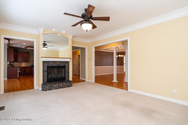 unfurnished living room featuring ornate columns, crown molding, carpet flooring, and a glass covered fireplace