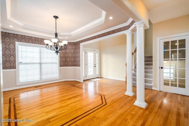 unfurnished dining area with a wainscoted wall, a raised ceiling, and wallpapered walls