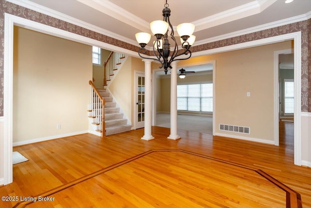 unfurnished dining area featuring wood finished floors, visible vents, stairs, plenty of natural light, and a raised ceiling