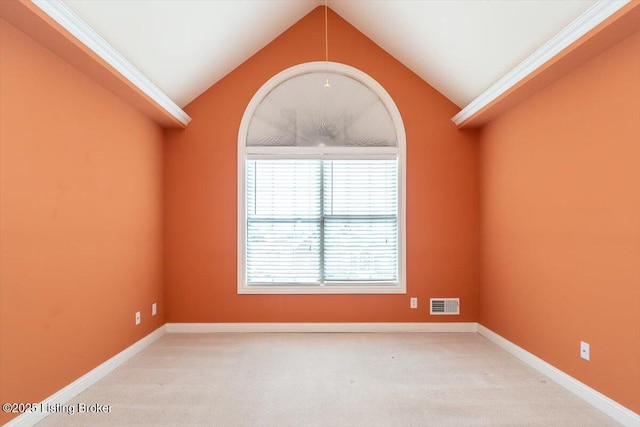 carpeted spare room featuring lofted ceiling, baseboards, and visible vents