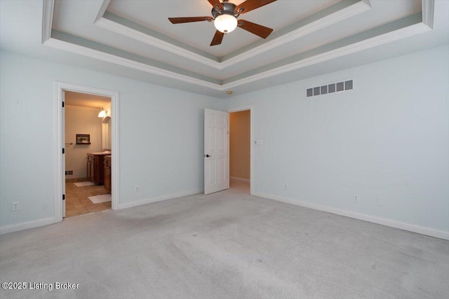 unfurnished bedroom featuring visible vents, baseboards, carpet, a tray ceiling, and crown molding