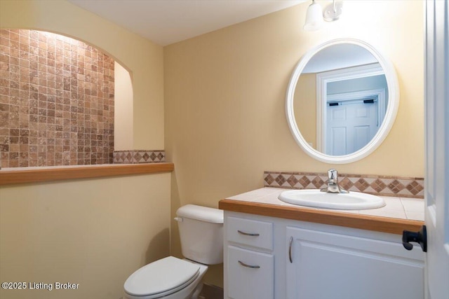 half bath with tasteful backsplash, vanity, and toilet