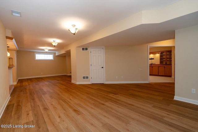 basement featuring light wood finished floors, visible vents, and baseboards