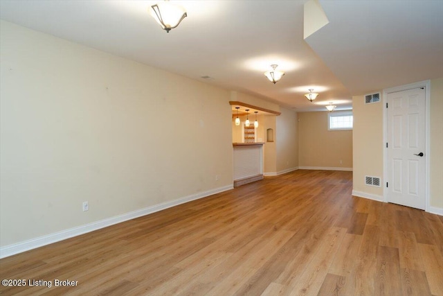 empty room featuring light wood finished floors, baseboards, and visible vents