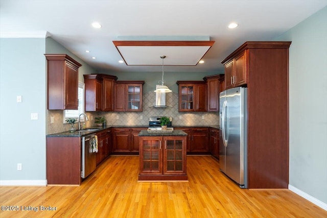 kitchen with stainless steel appliances, light wood-style floors, a sink, and tasteful backsplash