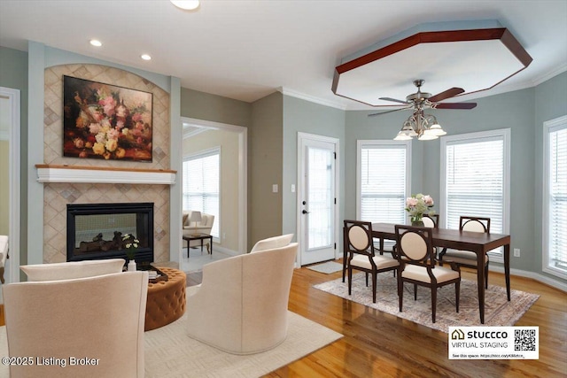 living area featuring crown molding, a tiled fireplace, and wood finished floors