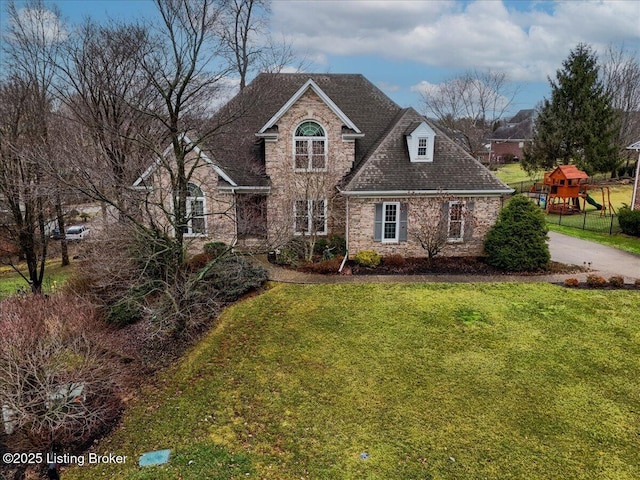 traditional home featuring stone siding and a front lawn