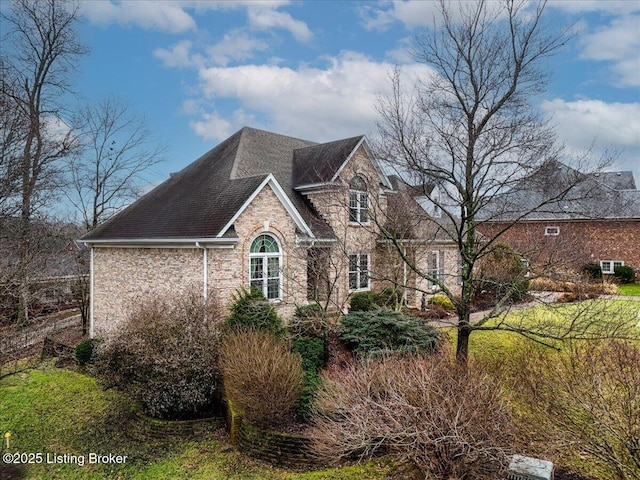 view of side of home featuring a shingled roof and stone siding