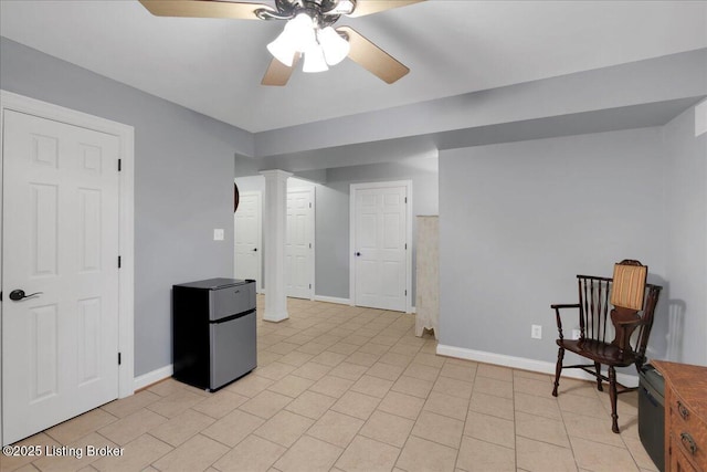 living area featuring ornate columns, ceiling fan, light tile patterned floors, and baseboards