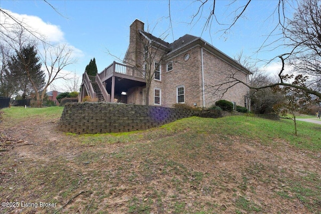 view of property exterior with a chimney, stairway, a deck, and a lawn