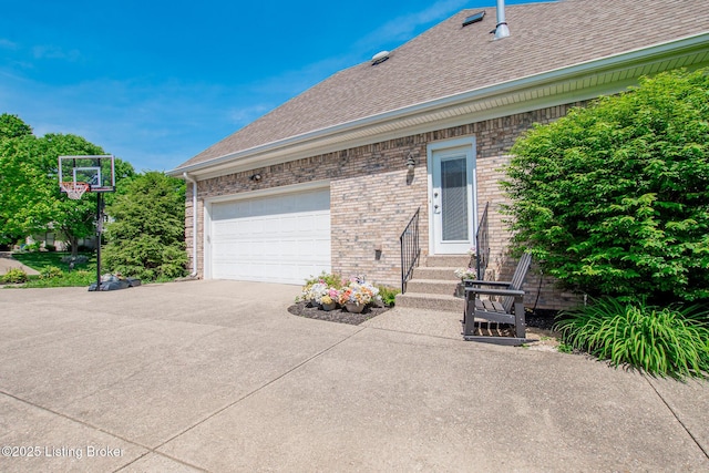 view of side of property featuring brick siding, a shingled roof, concrete driveway, an attached garage, and entry steps