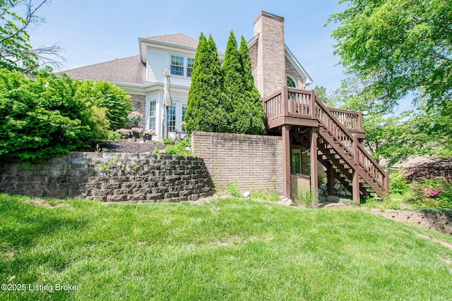 rear view of house with a chimney, stairway, a deck, and a yard