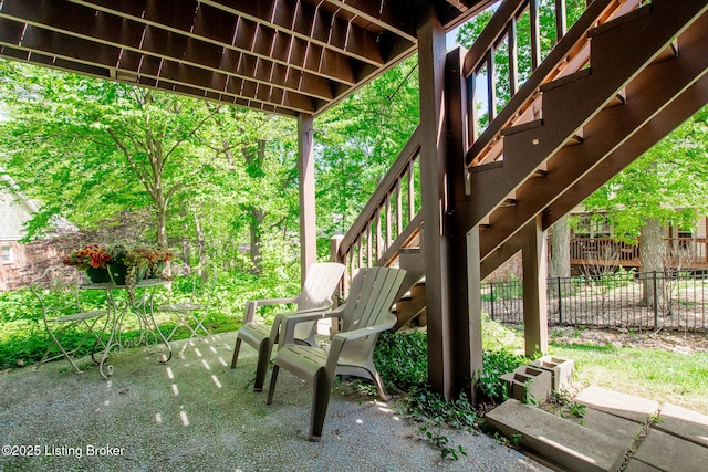 view of patio featuring fence and stairs