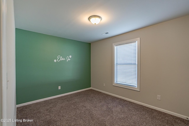 empty room featuring carpet floors, visible vents, and baseboards