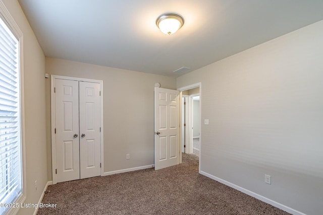 unfurnished bedroom featuring a closet, baseboards, carpet flooring, and multiple windows