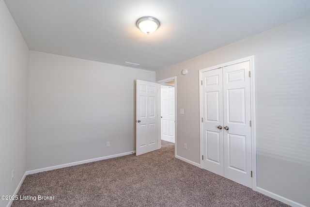 unfurnished bedroom featuring carpet floors, visible vents, baseboards, and a closet