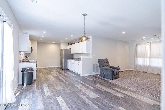 kitchen with open floor plan, white cabinetry, stainless steel fridge with ice dispenser, and wood finished floors