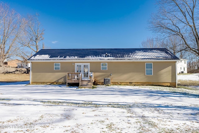 snow covered back of property featuring metal roof, central AC unit, crawl space, and french doors