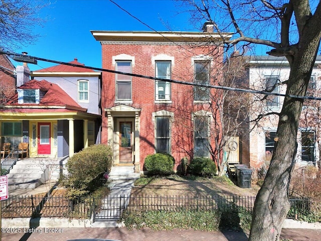 view of front facade with a fenced front yard, a chimney, and brick siding