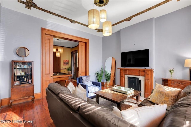 living area featuring a fireplace, baseboards, and dark wood finished floors