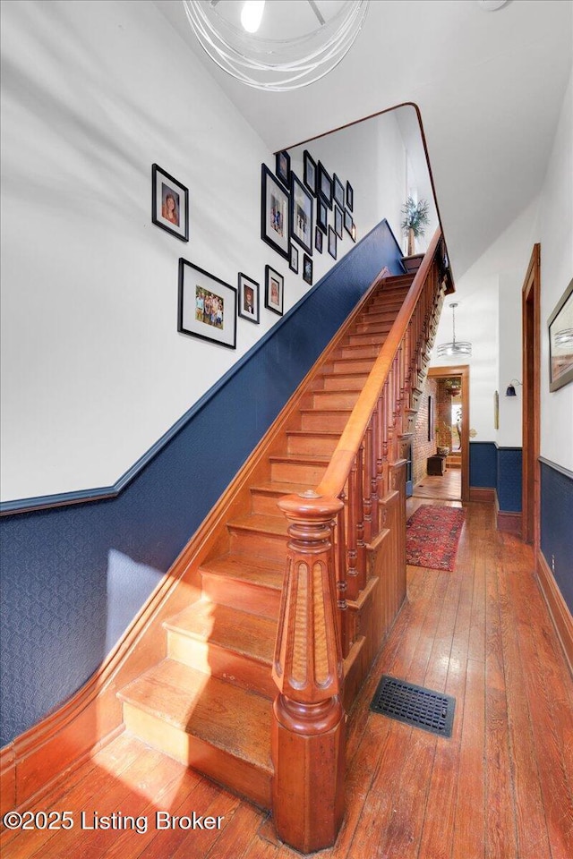 stairs with wood-type flooring, visible vents, and baseboards