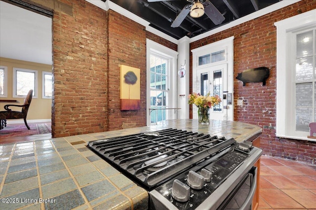 kitchen with brick wall, a wealth of natural light, tile patterned flooring, and tile counters