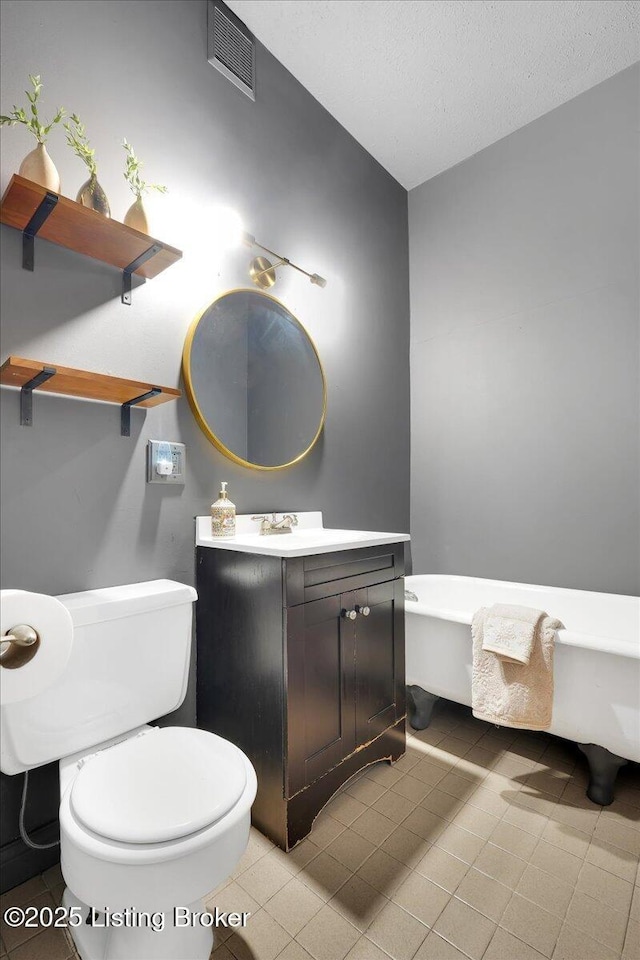 bathroom featuring toilet, a textured ceiling, vanity, and visible vents