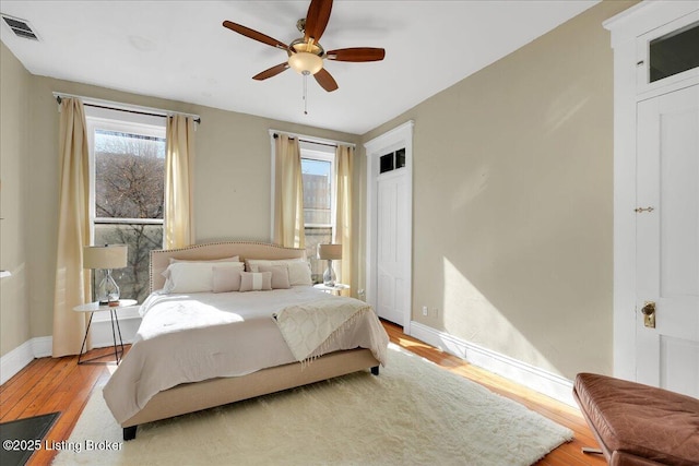 bedroom with baseboards, visible vents, ceiling fan, and wood finished floors