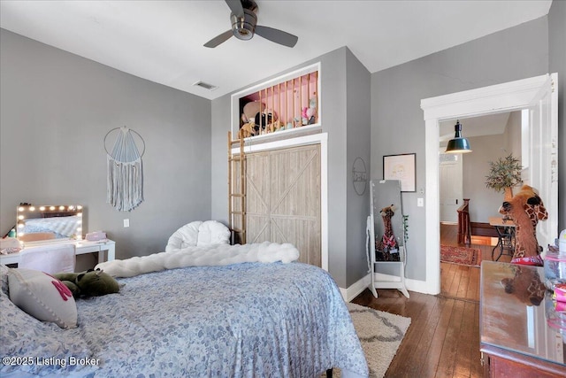 bedroom with ceiling fan, hardwood / wood-style flooring, visible vents, and baseboards