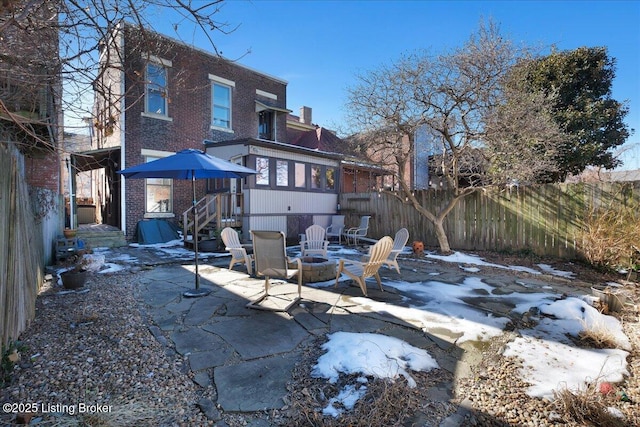 back of house featuring a fire pit, brick siding, a patio area, and fence