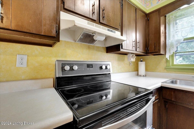 kitchen with stainless steel electric range oven, light countertops, a sink, and under cabinet range hood