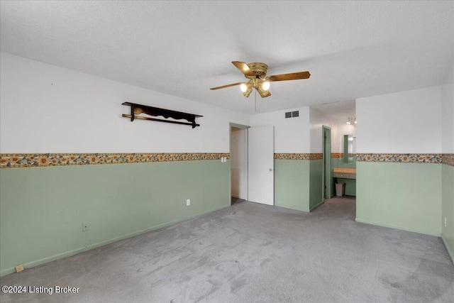 empty room featuring light colored carpet, visible vents, ceiling fan, and a textured ceiling