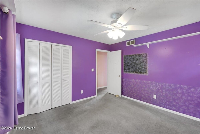 unfurnished bedroom with baseboards, visible vents, a textured ceiling, carpet floors, and a closet