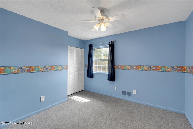 empty room with carpet floors, visible vents, a ceiling fan, a textured ceiling, and baseboards