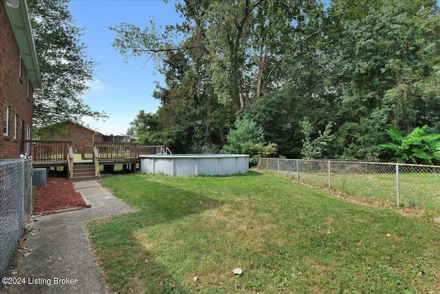 view of yard with central AC, a fenced backyard, a wooden deck, and a fenced in pool