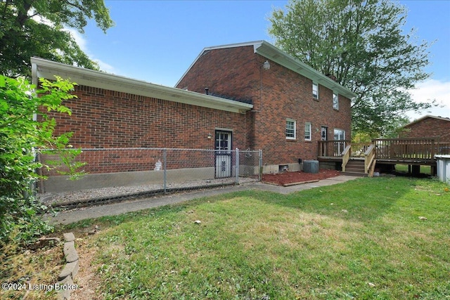 rear view of property with brick siding, a yard, fence, a deck, and cooling unit