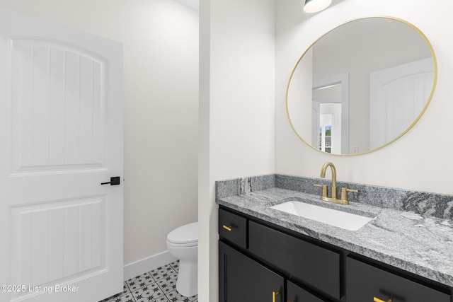 bathroom featuring baseboards, vanity, and toilet