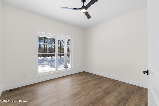 spare room featuring dark wood finished floors, visible vents, ceiling fan, a textured ceiling, and baseboards