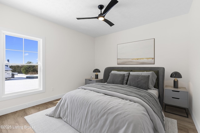 bedroom featuring ceiling fan, baseboards, and wood finished floors