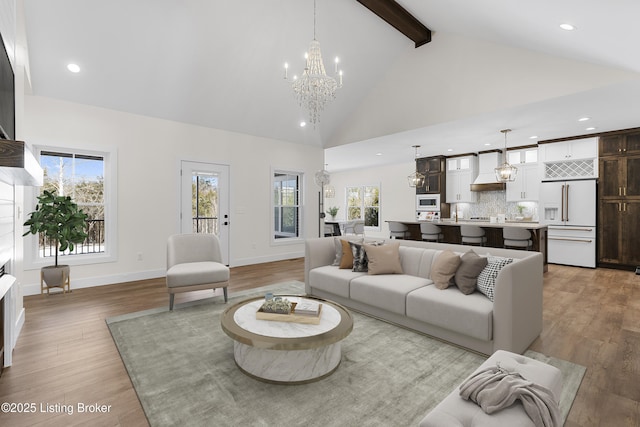 living area featuring light wood finished floors, high vaulted ceiling, beam ceiling, and an inviting chandelier