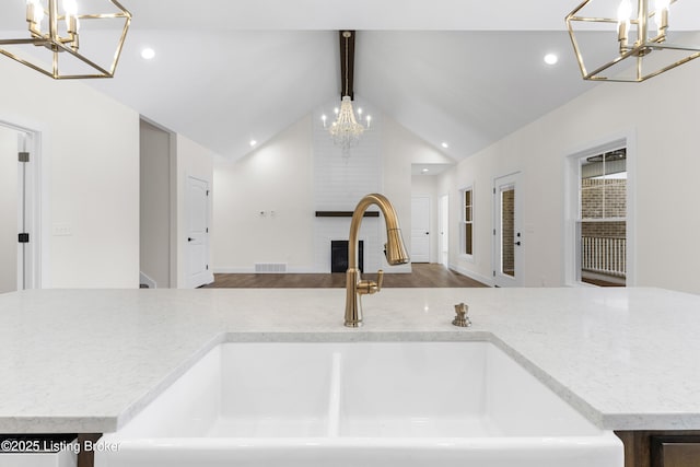 kitchen featuring a notable chandelier, visible vents, a large fireplace, a sink, and beamed ceiling