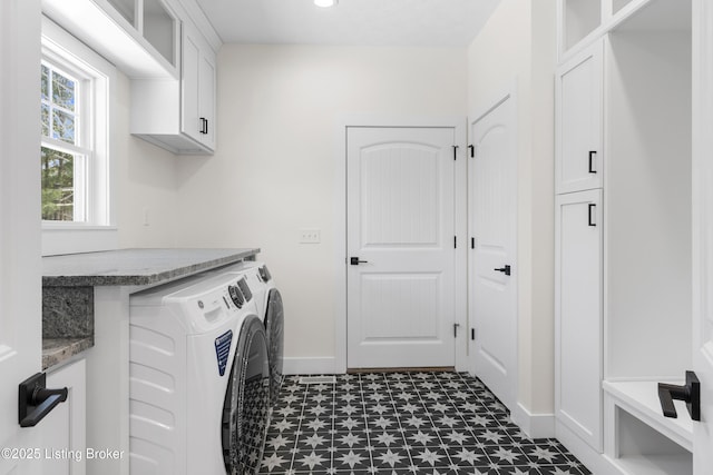 washroom featuring baseboards, dark floors, cabinet space, and washer and dryer