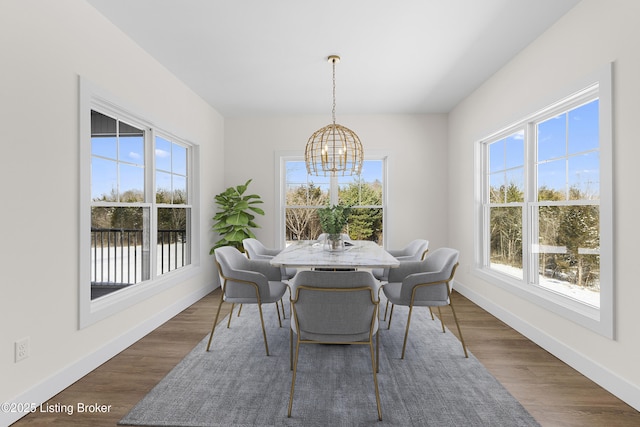 dining space with an inviting chandelier, baseboards, and wood finished floors