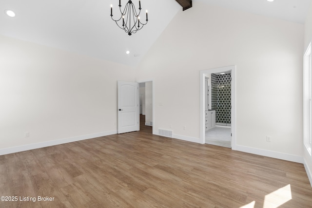 empty room with high vaulted ceiling, visible vents, baseboards, beam ceiling, and light wood finished floors