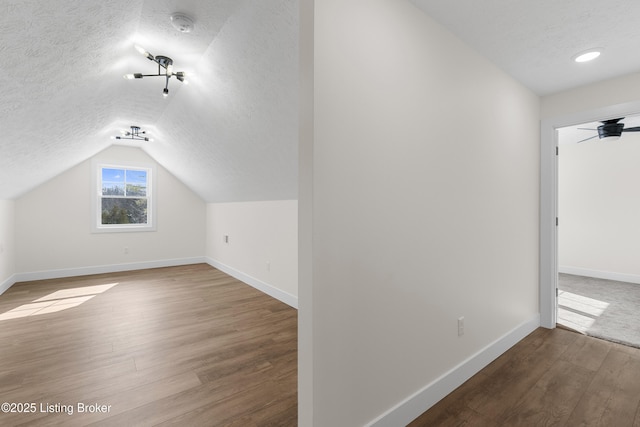 bonus room with lofted ceiling, baseboards, a textured ceiling, and wood finished floors