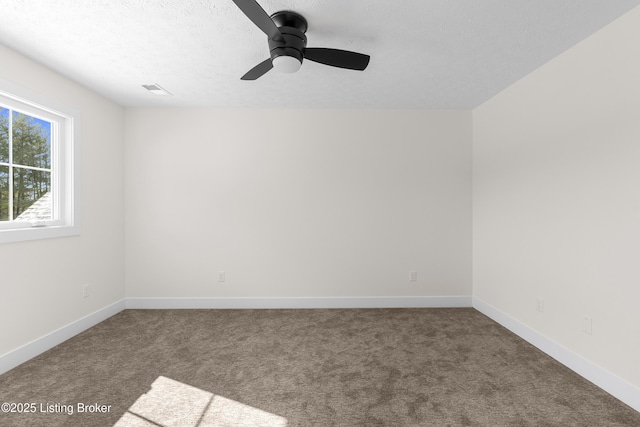 carpeted empty room featuring ceiling fan, visible vents, baseboards, and a textured ceiling