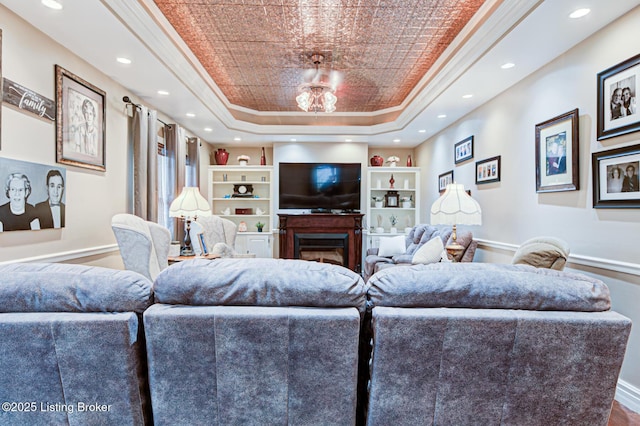 living room with a glass covered fireplace, a raised ceiling, crown molding, and recessed lighting